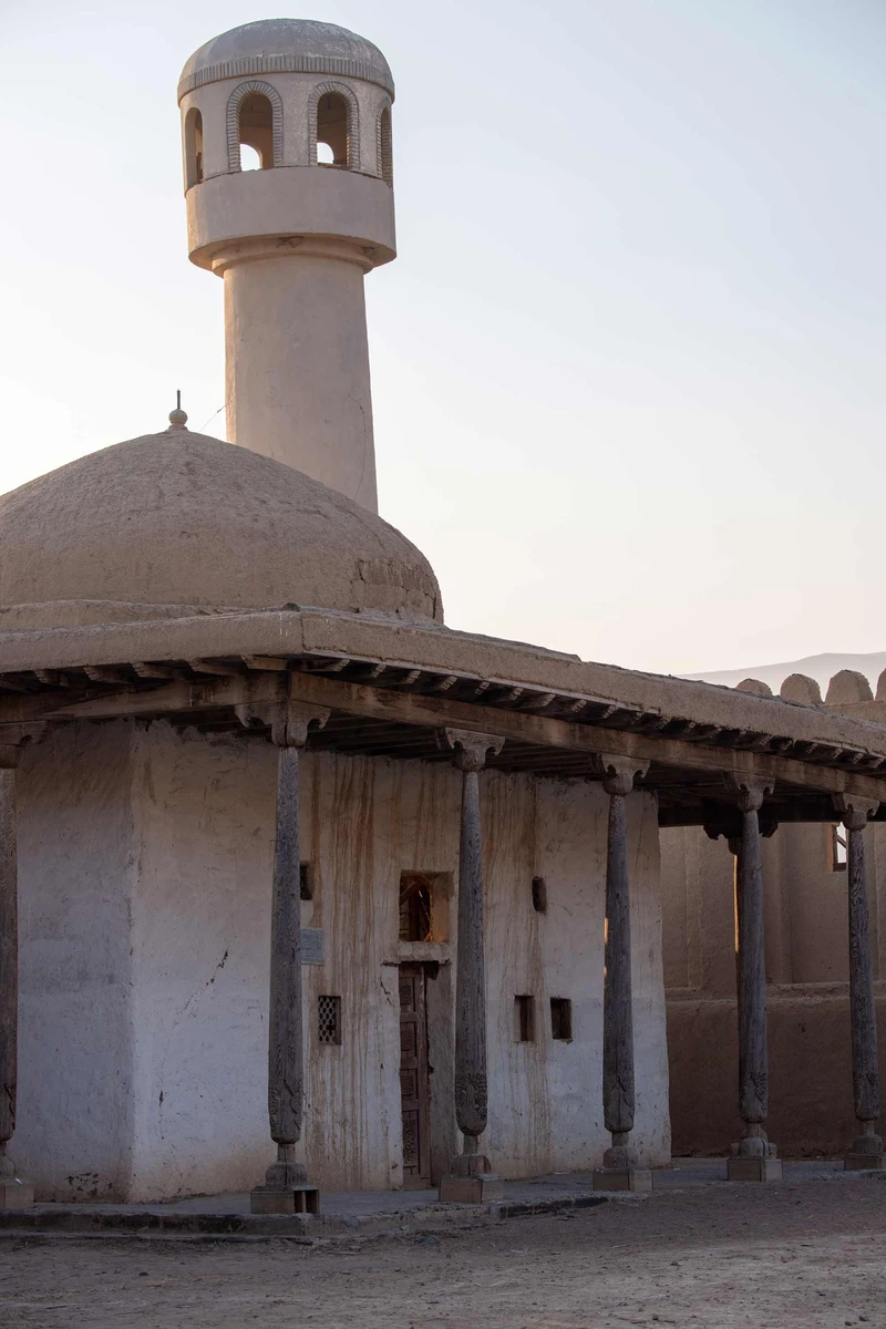 Mud-brick mosque with a dome and tall minaret at the nomad city film set